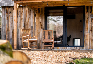 Natuurhuisje 'Barn' op Camping Si-Es-An in Nederland, met twee houten stoelen op de veranda.
