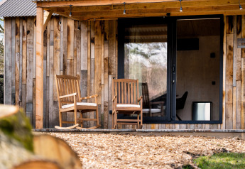 Casa de naturaleza 'Barn' en el camping Si-Es-An, Países Bajos, con dos sillas de madera en la veranda.