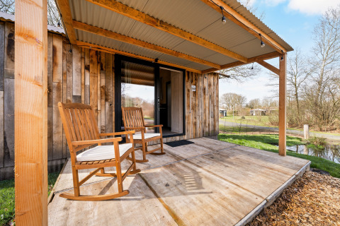 Veranda in legno con sedie a dondolo al nature house 'Barn' nel campeggio Si-Es-An nei Paesi Bassi.