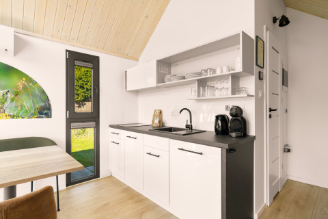 Coin cuisine moderne dans une tiny house au camping Si-Es-An, Pays-Bas, avec meubles blancs et bois clair.