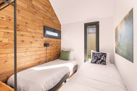 Bright twin bedroom inside a tiny house at Campsite Si-Es-An in the Netherlands, with wood panel décor.
