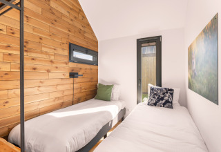 Bright twin bedroom inside a tiny house at Campsite Si-Es-An in the Netherlands, with wood panel décor.