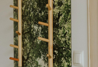 Wooden pegs on a wall decorated with a forest mural in a tiny house at Campsite Si-Es-An, Netherlands.