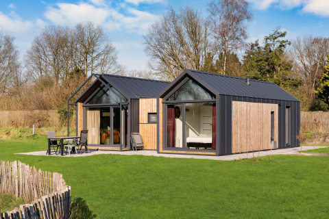 Contemporary Cosy Lodge with large windows at Campsite Si-Es-An, surrounded by greenery in the Netherlands.