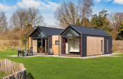 Contemporary Cosy Lodge with large windows at Campsite Si-Es-An, surrounded by greenery in the Netherlands.