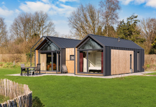 Moderne, hyggelig lodge med store vinduer og træbeklædning på Campingplads Si-Es-An i Holland.