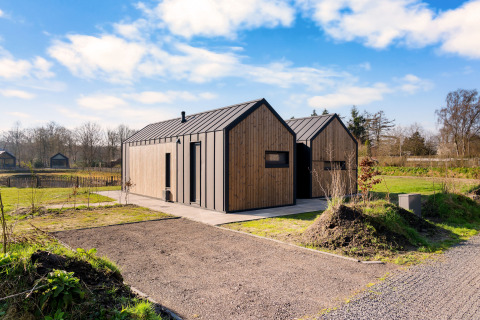 En moderne træhytte ved Cosy Lodge på Campingplads Si-Es-An, Holland, under en klar blå himmel.