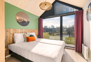 Lyst soveværelse i Cosy Lodge på Campingplads Si-Es-An i Holland med stor vindue og naturskøn udsigt.