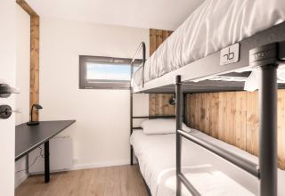 Room with bunk bed, desk, and window at Cosy Lodge, Campsite Si-Es-An, Netherlands.
