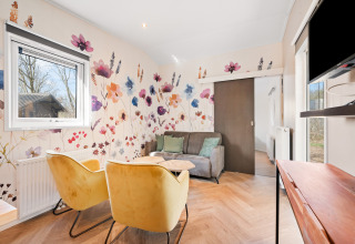 Acogedora sala en Happy bee lodge, en el Camping Si-Es-An, Países Bajos, con arte floral en la pared y sillones modernos.