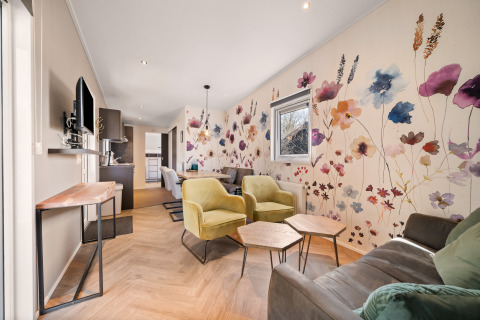 Living area in Happy bee lodge at Campsite Si-Es-An, Netherlands, featuring floral wall art and modern seating.