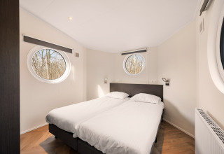 Modern bedroom with twin beds and round windows at Happy bee lodge, Campsite Si-Es-An, Netherlands.
