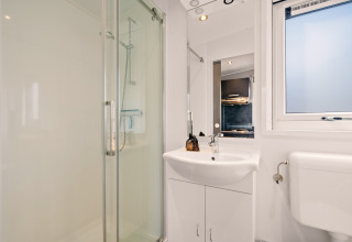 Modern bathroom at Happy Bee Lodge, Si-Es-An Campsite, Netherlands, showing shower, sink and toilet.