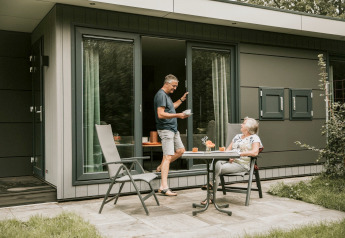 Älteres Paar entspannt sich auf der Terrasse eines Tiny Houses namens Luxury Loft mit Kaffee und Kuchen.