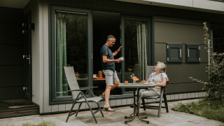 Coppia anziana si gode il caffè all’aperto davanti a una tiny house chiamata Luxury Loft, sul patio.