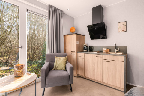 Moderna tiny house con angolo cottura e poltrona in Luxury Loft al campeggio Si-Es-An, Paesi Bassi, natura vista.