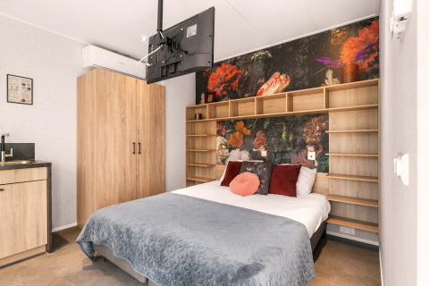 Loft di lusso in tiny house al campeggio Si-Es-An, Paesi Bassi, con letto moderno e arte floreale.