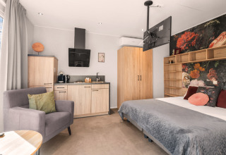 Casa tiny house tipo loft de lujo con cocina y cama acogedora en el camping Si-Es-An en los Países Bajos.