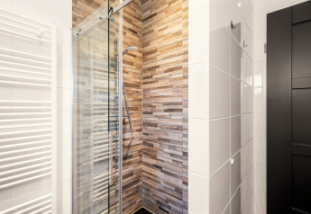 Moderne douche met glazen deur en houtlook tegels in de compacte badkamer van Luxury Loft op Si-Es-An.