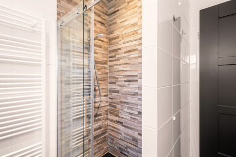 Doccia moderna con porta in vetro e piastrelle effetto legno nel bagno compatto del Luxury Loft a Si-Es-An.