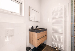 Baño moderno en la tiny house Luxury loft en el Campsite Si-Es-An, Países Bajos, con lavabo de madera.