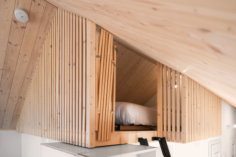 Soveloft med trælameller og skrånende loft på Reestdal-lodgen ved Campingplads Si-Es-An i Holland.