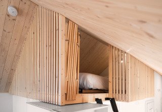Soveloft med trælameller og skrånende loft på Reestdal-lodgen ved Campingplads Si-Es-An i Holland.