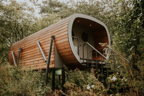 Modern wooden Skycabin on stilts surrounded by greenery at Campsite Si-Es-An in the Netherlands.