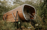 Modern wooden Skycabin on stilts surrounded by greenery at Campsite Si-Es-An in the Netherlands.