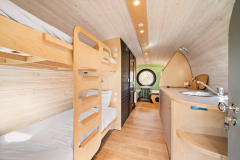 Interieur van de Skycabin op Camping Si-Es-An in Nederland met stapelbedden, keukentje en zithoek.