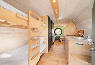 Interieur van de Skycabin op Camping Si-Es-An in Nederland met stapelbedden, keukentje en zithoek.