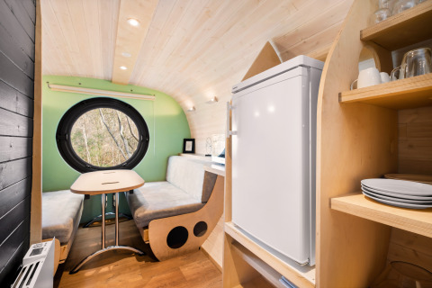 Interieur van de Skycabin op Camping Si-Es-An, Nederland, met zithoek, rond raam en keukentje.