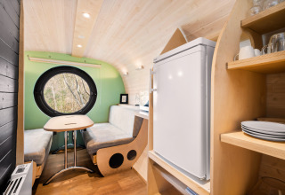 Interieur van de Skycabin op Camping Si-Es-An, Nederland, met zithoek, rond raam en keukentje.