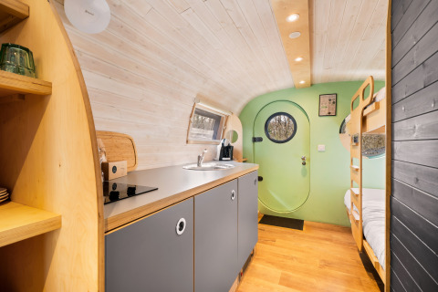 Modern, compact interior of Skycabin at Campsite Si-Es-An, featuring a kitchen and bunk beds, Netherlands.
