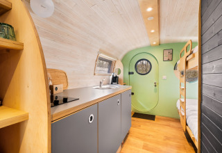 Modern, compact interior of Skycabin at Campsite Si-Es-An, featuring a kitchen and bunk beds, Netherlands.
