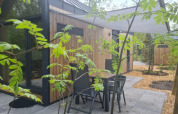 Terraza exterior de una tiny house en el camping Si-Es-An, Países Bajos, rodeada de vegetación y árboles.