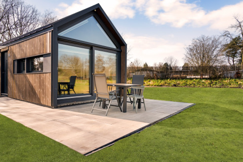 Lodge moderno 'Reestdal' al campeggio Si-Es-An nei Paesi Bassi con patio e giardino verde.