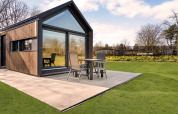Lodge moderno 'Reestdal' al campeggio Si-Es-An nei Paesi Bassi con patio e giardino verde.
