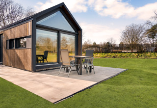 Lodge moderno 'Reestdal' al campeggio Si-Es-An nei Paesi Bassi con patio e giardino verde.
