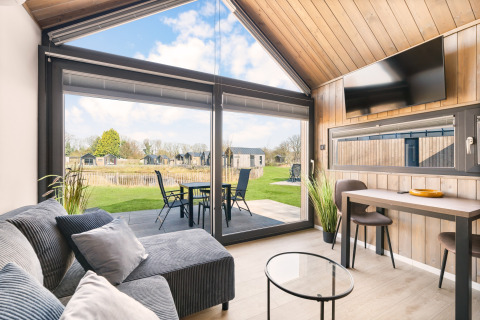 Modernes Reestdal-Lodge am Campingplatz Si-Es-An in den Niederlanden mit Panoramafenster und Gartenblick.