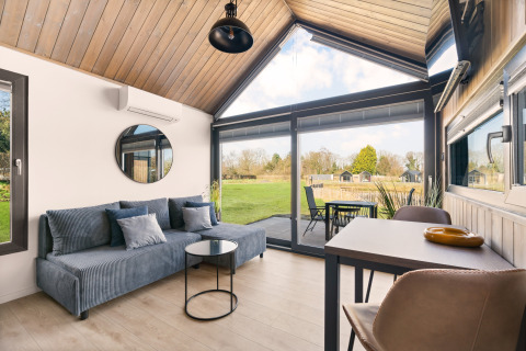 Modernes Lodge-Wohnzimmer mit großen Fenstern und Blick ins Grüne im Reestdal Loft, Si-Es-An, Niederlande.