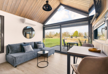 Modernes Lodge-Wohnzimmer mit großen Fenstern und Blick ins Grüne im Reestdal Loft, Si-Es-An, Niederlande.