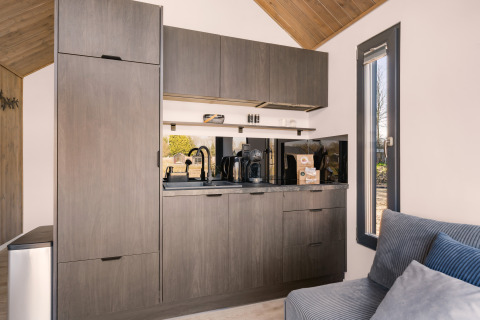 Cocina moderna con gabinetes grises en el loft «Reestdal» del Camping Si-Es-An en los Países Bajos.