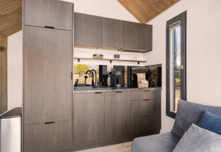 Modern kitchenette with gray cabinets and appliances in «Reestdal» loft at Campsite Si-Es-An, Netherlands.
