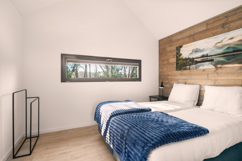 Modernes Schlafzimmer im Reestdal-Loft mit zwei Einzelbetten, Holzverkleidung und langem Fenster.