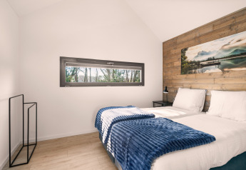 Camera doppia luminosa e moderna nel loft Reestdal con parete in legno e ampia finestra panoramica.