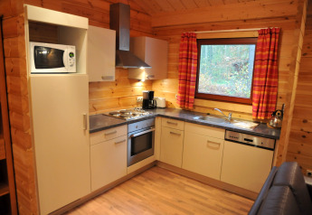 Moderne Küche im Holzchalet ‘De Boshut’ in Belgien mit Geräten, Fenster und Holzverkleidung.