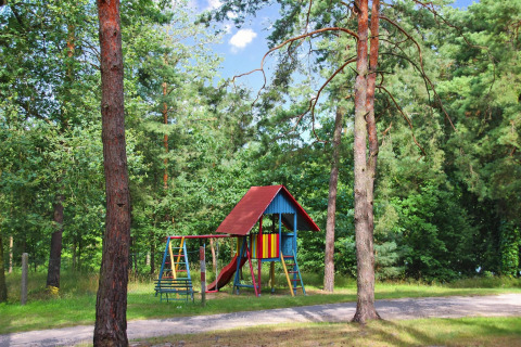 Speeltuin met schommels en glijbaan tussen bomen aan Bungalow '50 qm 5 Pers' in Duitsland.