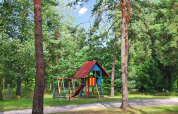 Speeltuin met schommels en glijbaan tussen bomen aan Bungalow '50 qm 5 Pers' in Duitsland.