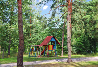 Parco giochi con altalene e scivolo tra gli alberi presso Bungalow '50 qm 5 Pers' in Germania.